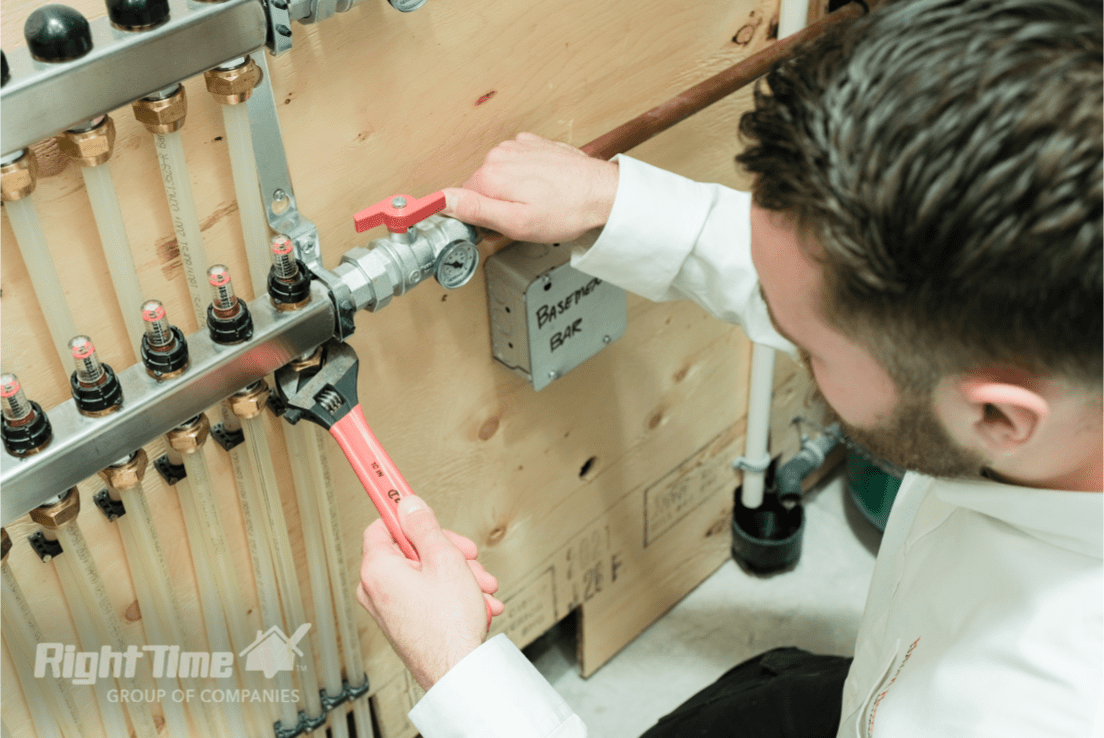 HVAC technician in Toronto adjusting furnace valve with wrench to fix cold air blowing issue, surrounded by heating system pipes and fittings