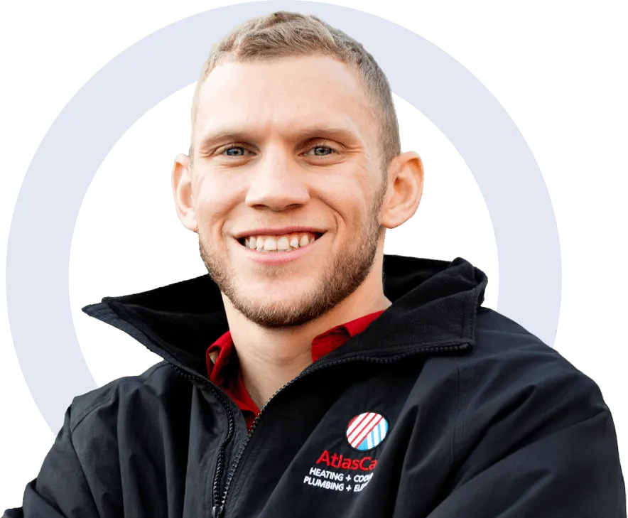 AtlasCare team member in an issued black zip-up jacket with a popped red inner collar, smiling broadly with teeth visible.