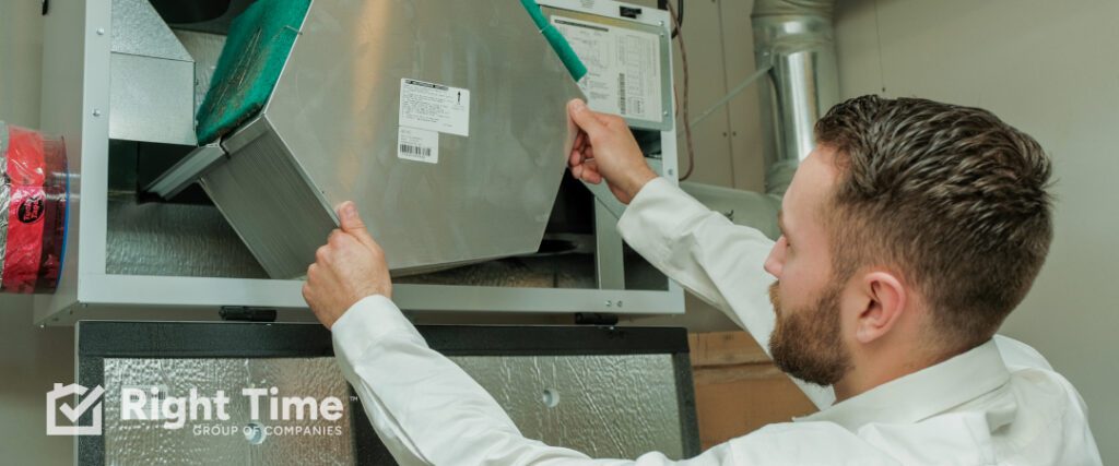 Technician inspecting a whole-home HVAC filter inside an air handler during spring maintenance to support cleaner indoor air and smooth cooling.